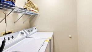 A laundry room with a washing machine and dryer, a metal drying rack, and a wall-mounted shelf with folded towels. - Long Range Views, Firepit, Hot tub, Game Room (Beech Mountain)