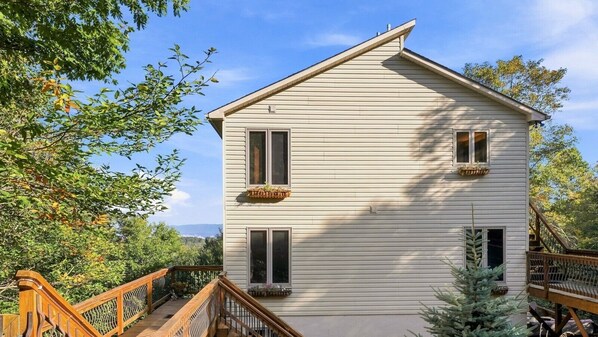 Ein zweistöckiges Haus mit einer Holzterrasse und einer Treppe.