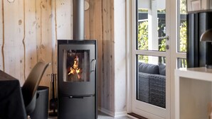 Een modern interieur met een houtkachel, een eethoek en een uitzicht door een glazen deur.
