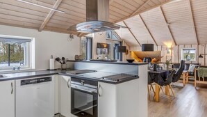 Een moderne keuken met een centraal eiland, een ingebouwde oven en een eethoek met een tafel en stoelen.