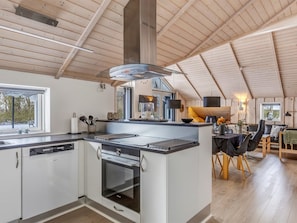 A modern kitchen with a central island, built-in oven, and a dining area with a table and chairs.