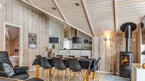 Een modern interieur met een eetgedeelte, een zwarte leren bank en een ruimte met houten lambrisering.