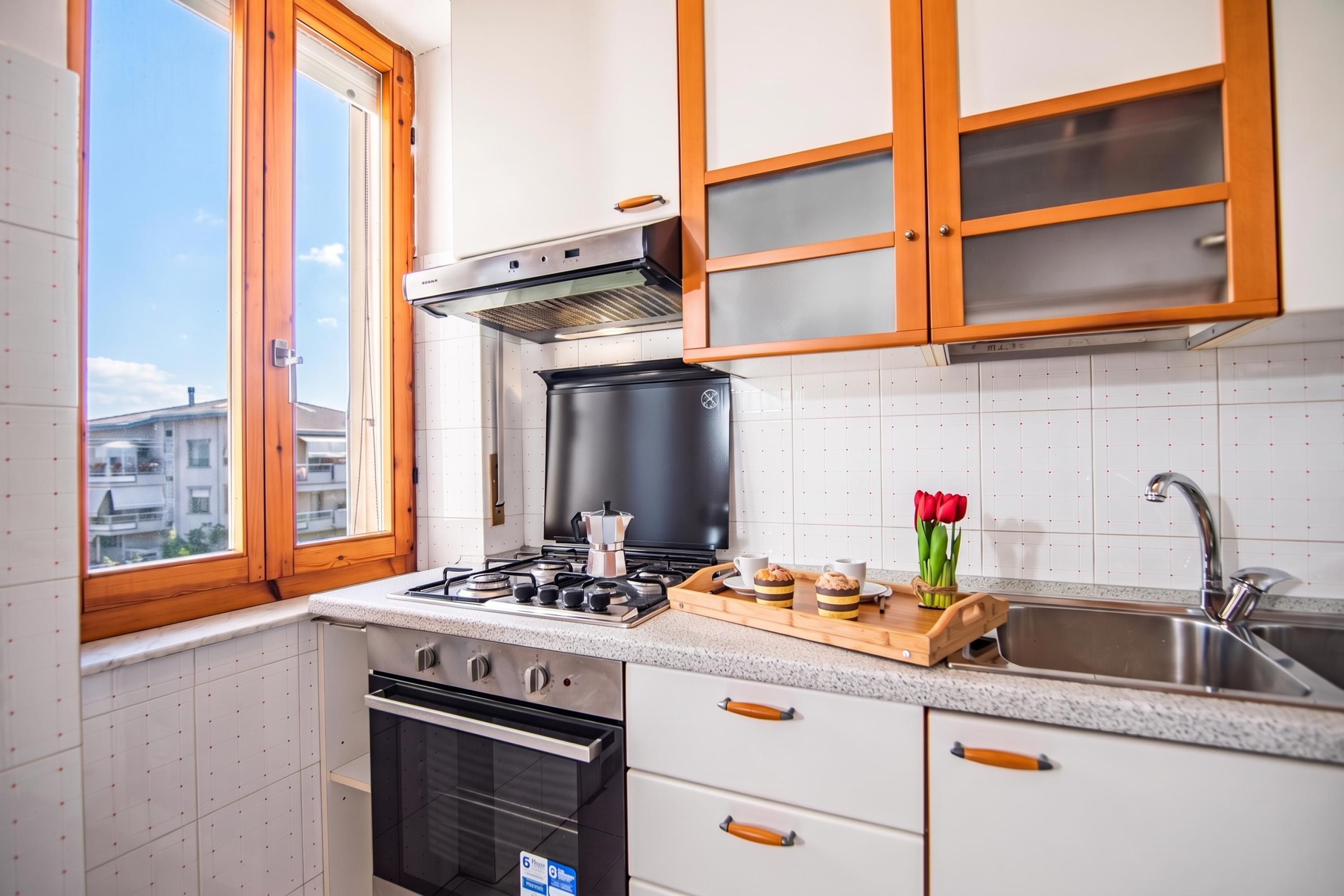 A kitchen with a gas stove, oven, and a window with wooden frames.