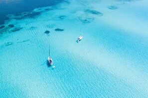 An aerial view of a clear blue sea with two boats.