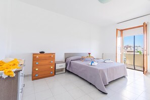 Et soveværelse med seng, kommode og balkon med udsigt.