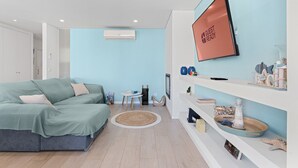 A modern bedroom with a bed, a TV, a small table, and decorative items. - GuestReady - Relaxing escape near the beach (Moledo)