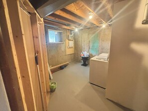 Ein schmaler Korridor mit Holzboden, einem Fenster und einer Waschmaschine.