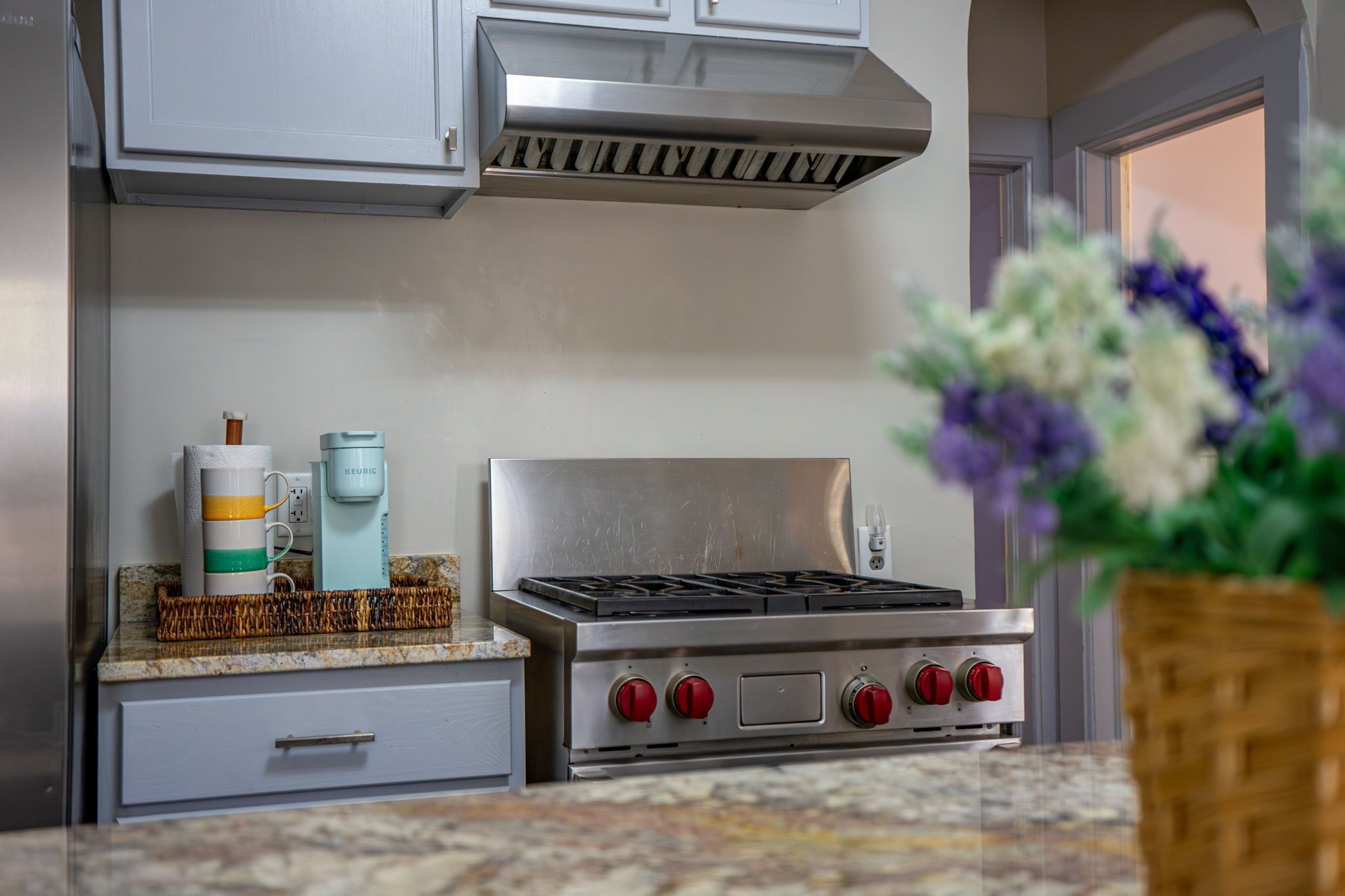 A kitchen with a stainless steel stove, a coffee maker, and a basket on the counter.