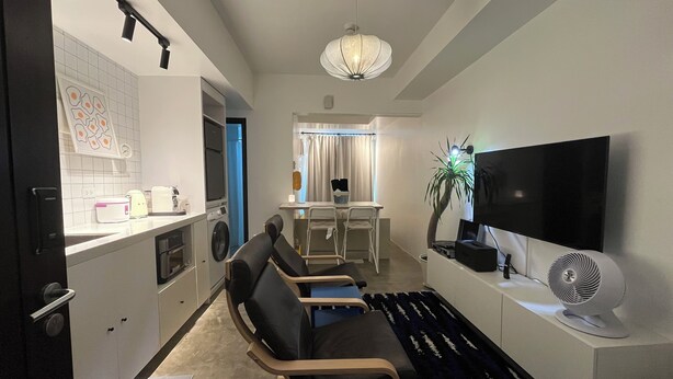 Un salon moderne doté d’un téléviseur à écran plat, d’un coin repas et d’une cuisine équipée d’un lave-linge.