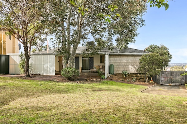 A spacious backyard shaded with trees. Lay on a picnic rug or let the kids play