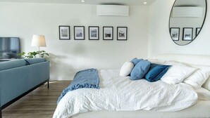 Ein modernes Schlafzimmer mit Bett, Sofa, Fernseher und gerahmten Bildern an der Wand.