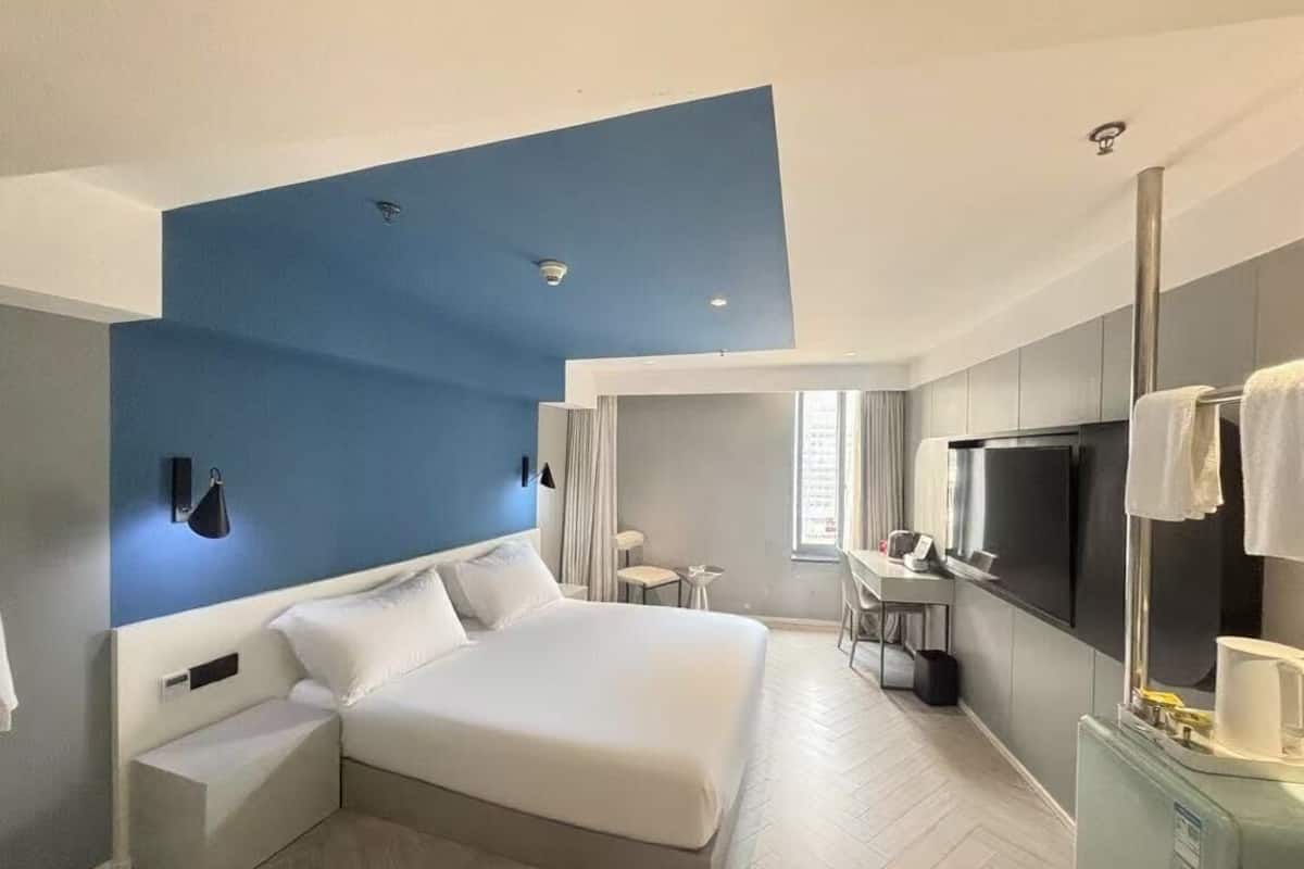 Ein modernes Hotelzimmer mit einem großen Bett, einem Schreibtisch und einem Fernseher.