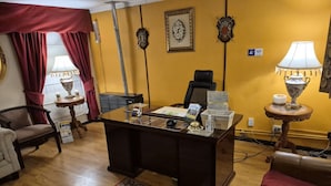 A room with a wooden desk, a chair, a sofa, and a patterned rug. - Hostal Oasis (Puerto Natales)