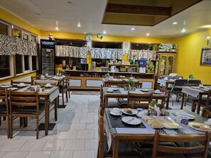 A restaurant with multiple tables and chairs, a clock, and a vending machine. - Hostal Oasis (Puerto Natales)