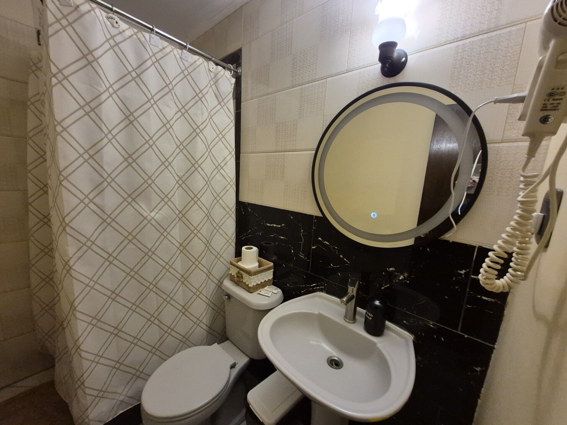 Un baño con inodoro, lavamanos y espejo.