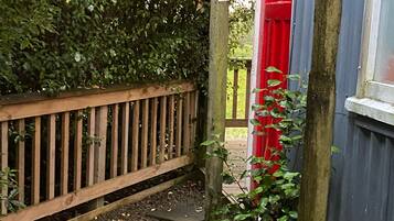 A wooden pergola with a wooden deck, stone steps, and a red door.
