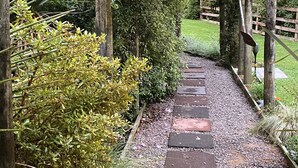 Una pérgola de madera con un camino de grava que conduce a una valla de madera.