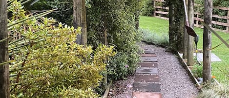 A wooden pergola with a gravel pathway leading to a wooden fence.