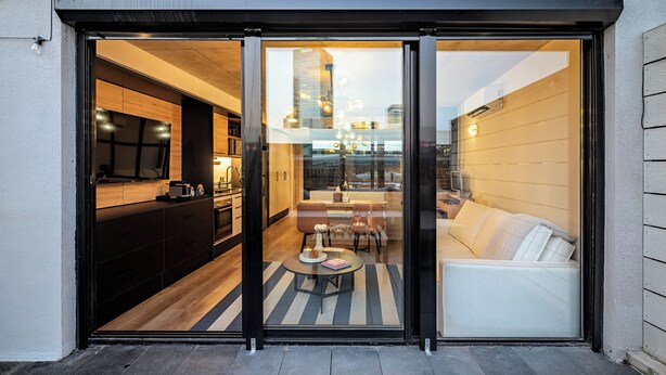 Un interior moderno con cocina, comedor y sala de estar visibles a través de puertas de vidrio.