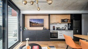 Una cocina moderna con un ventanal grande, un comedor con sillas naranjas y una mesa negra.