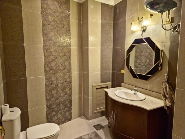 A bathroom with a toilet, sink, and mirror.