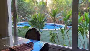 A room with a large window overlooking a pool and lush greenery. - Fully furnished, luxury villa located in Diplomatic Compound in New Cairo. (New Cairo)