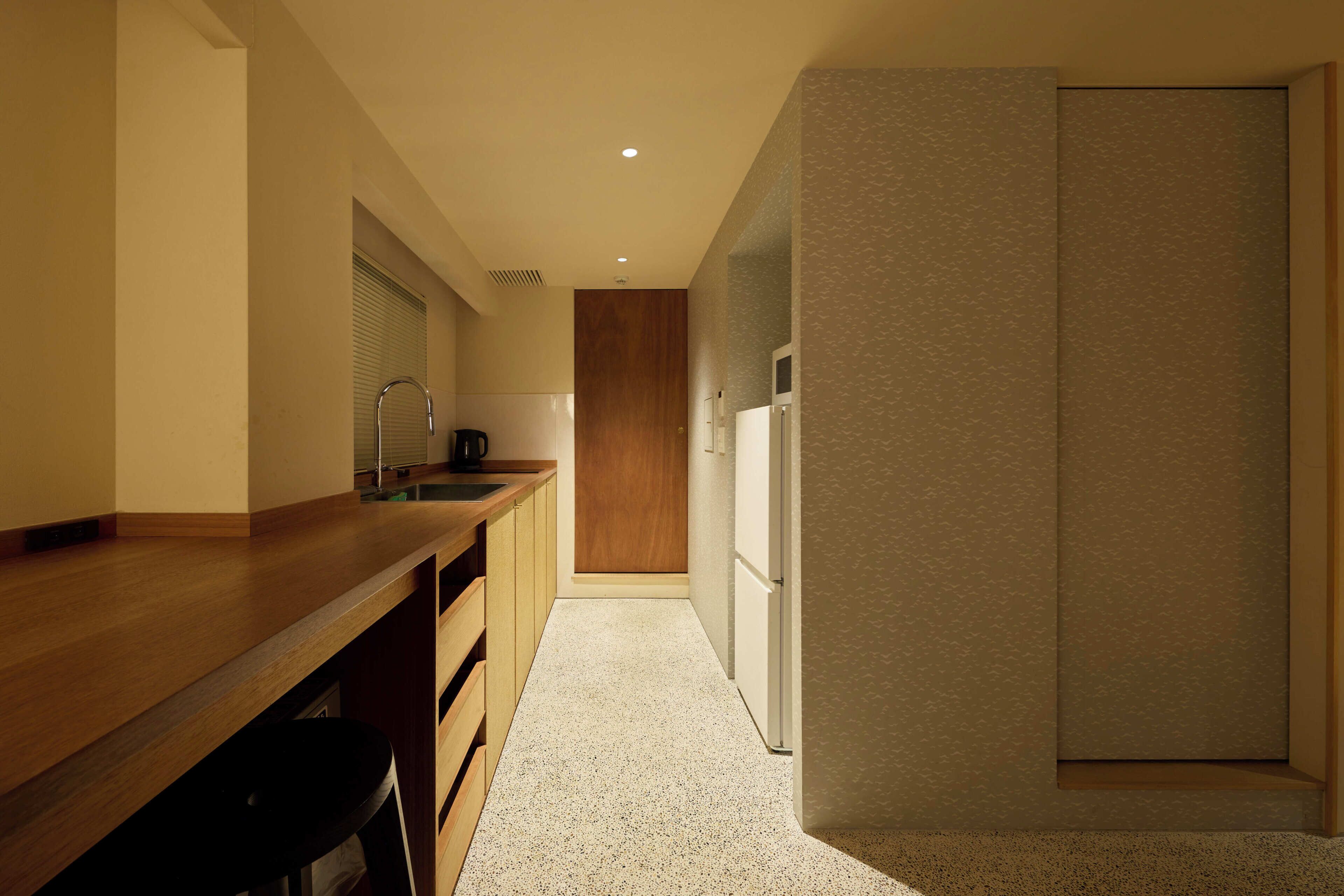 A modern kitchen with a wooden countertop, a sink, and a refrigerator.