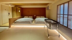 Ett modernt hotellrum med två sängar, ett träpanelat tak och ett stort fönster med persienner.