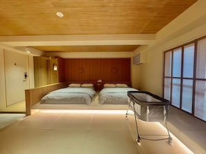 Une chambre d’hôtel moderne avec deux lits, un plafond en bois et une grande fenêtre équipée de stores.