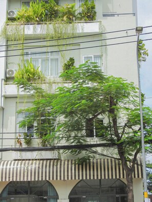 A multi-story building with balconies adorned with various plants.