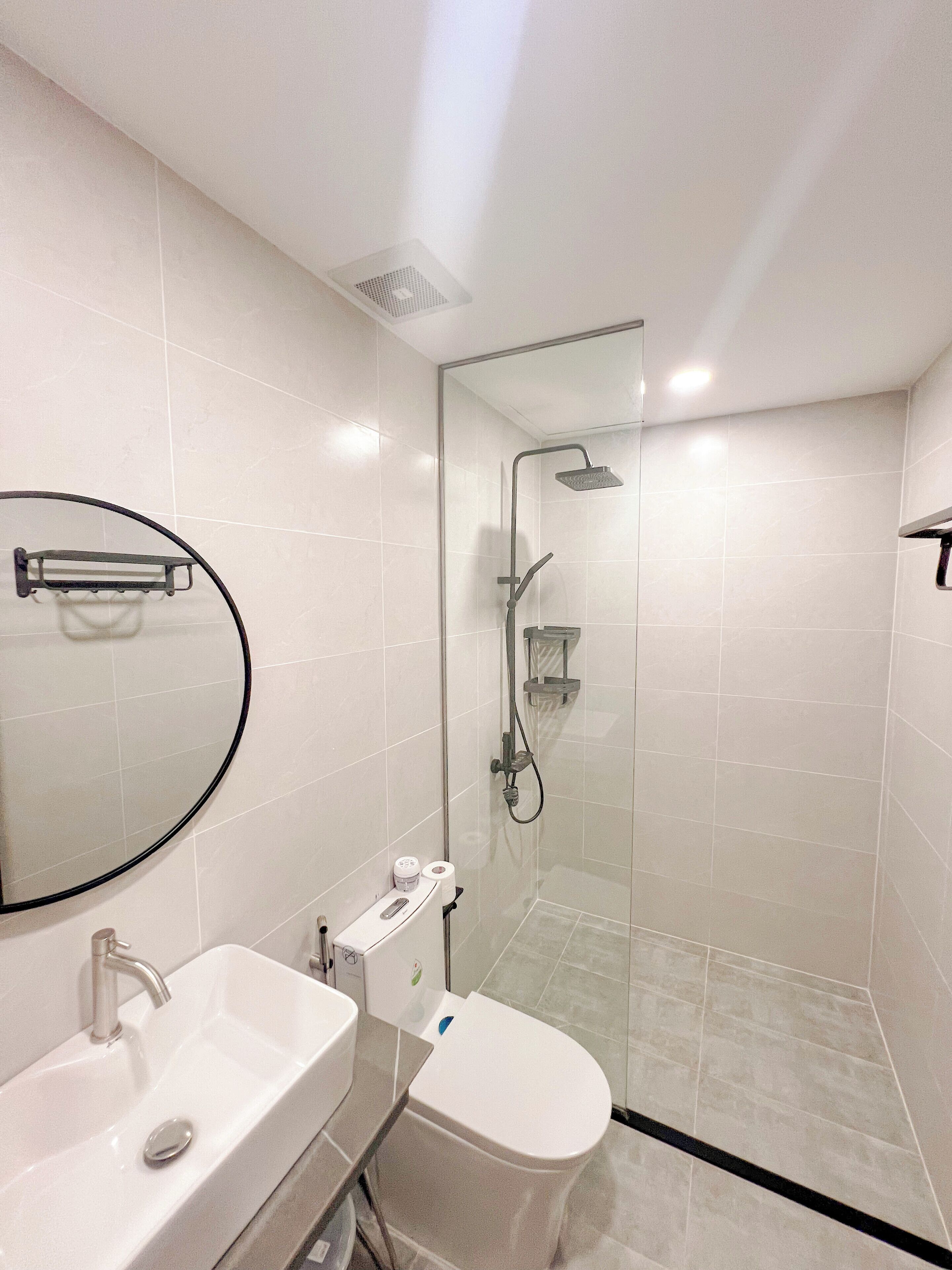 Un baño moderno con ducha acristalada, lavabo blanco y un inodoro.