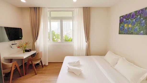 Una camera d'albergo con un letto, una scrivania, una sedia, una televisione e una finestra con tende.