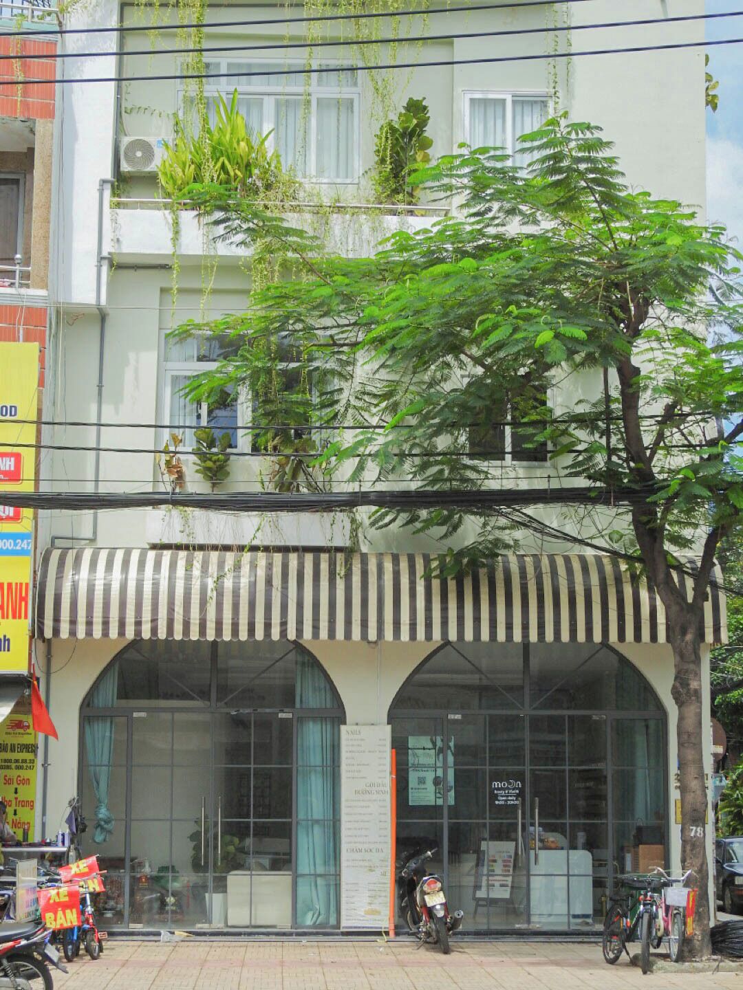 Un edificio con escaparate que presenta un toldo a rayas y amplios ventanales.