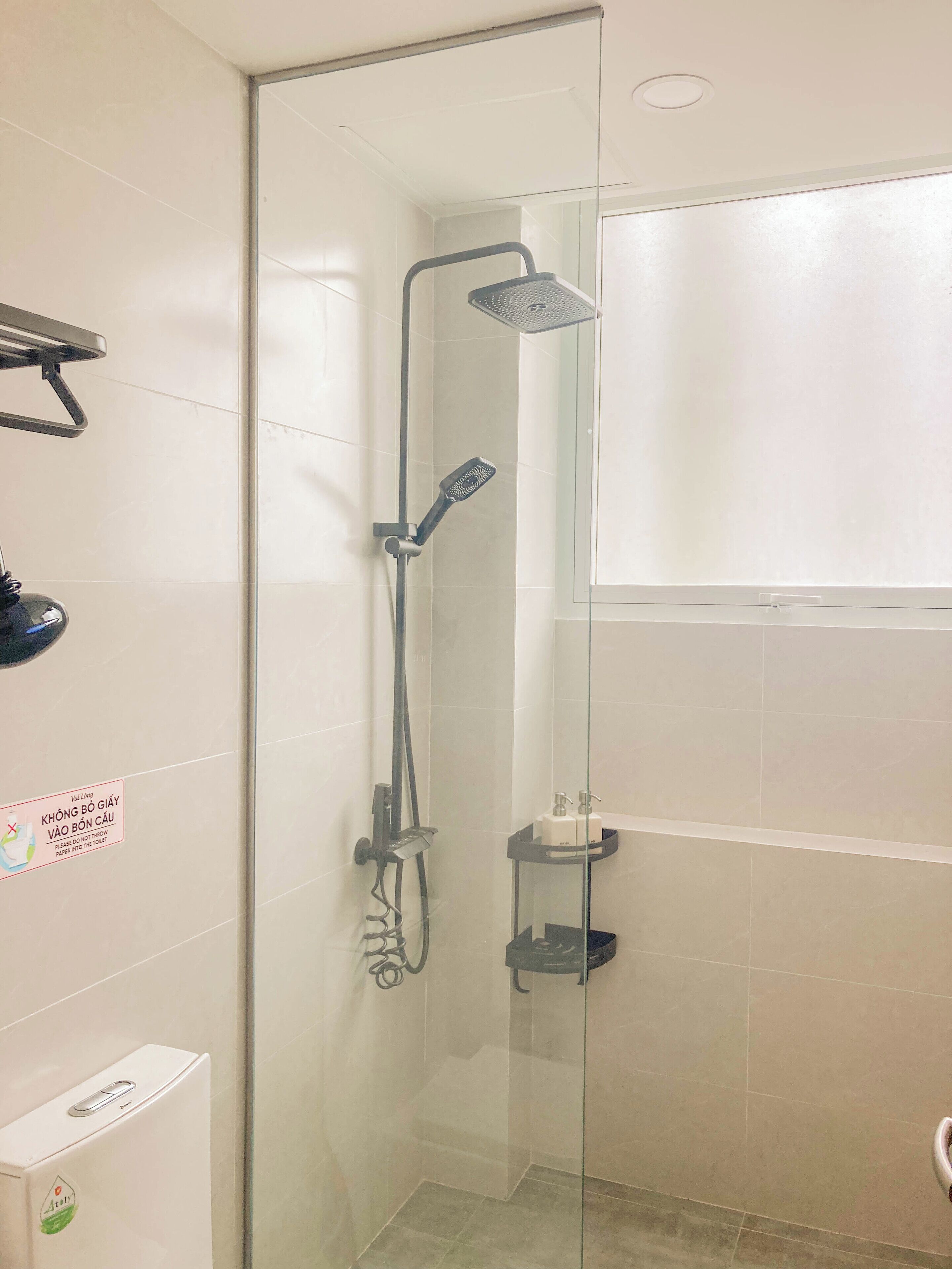 A glass-enclosed shower stall with a handheld showerhead and a wall-mounted faucet.