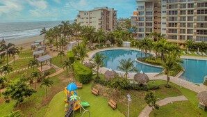 A resort with a pool, palm trees, and a beach view. - Stunning Oceanfront Apartment in Playa Caracol · Chame · Panama (Provincia de Panamá Oeste)