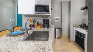 A compact kitchen with a microwave, sink, and stove. - Stunning Oceanfront Apartment in Playa Caracol · Chame · Panama (Provincia de Panamá Oeste)