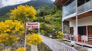 Une enseigne indiquant l’emplacement du Yamunotri Heli Resort, avec une vue sur le paysage montagneux environnant.