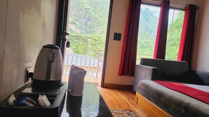 Une pièce comprenant un canapé, une machine à café, une poubelle et donnant sur un balcon avec une balustrade.