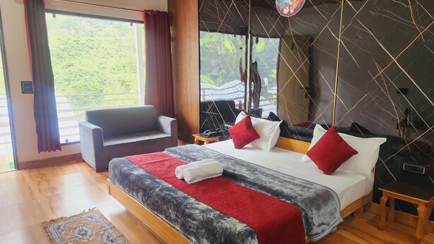Une chambre d’hôtel avec un grand lit, un canapé, une petite table et une vue sur la verdure.