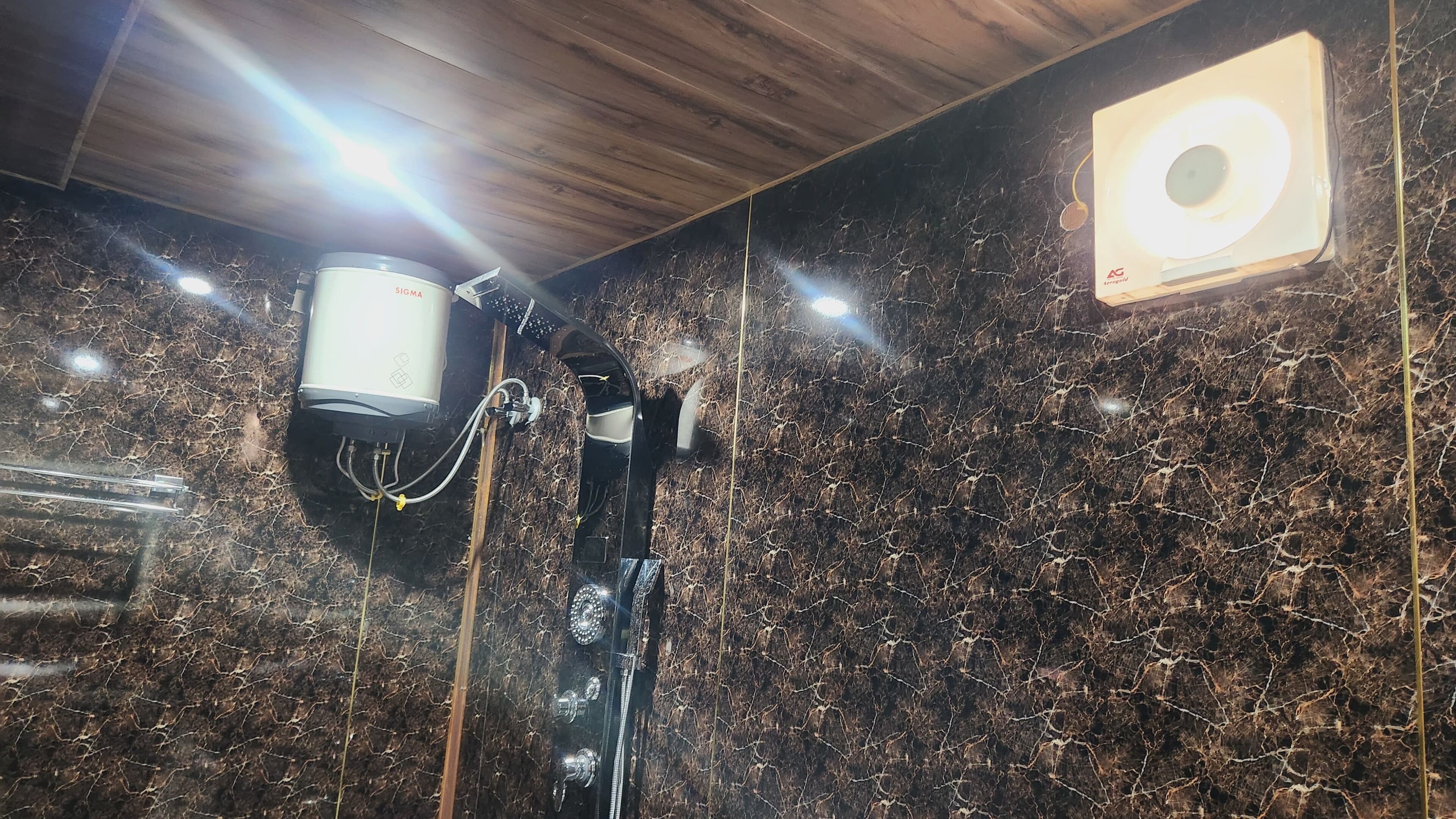 A marble wall with a ceiling light fixture and a smoke detector.