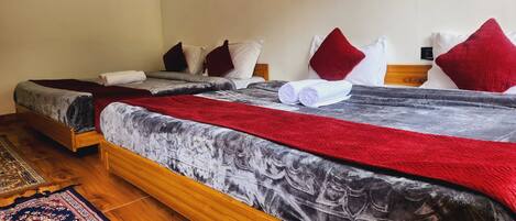 A double bed with a red and grey blanket, two pillows, and a wooden headboard.