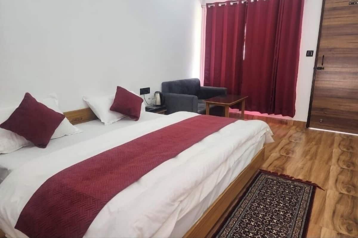 Un dormitorio con cama, una silla, una mesita y una puerta.