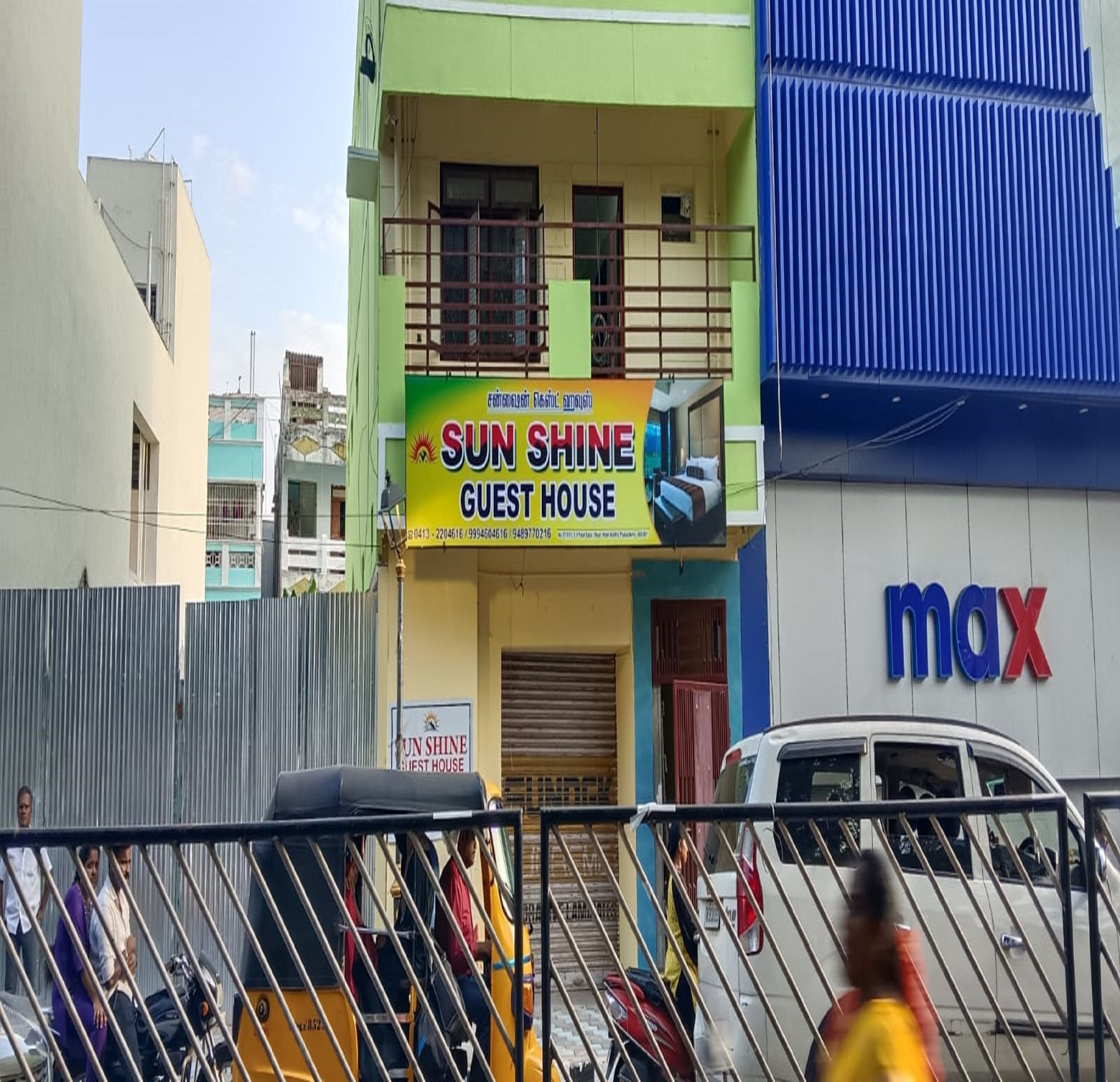 Un edificio con un cartel que dice 'Sun Shine Guest House' y una tienda 'Max'.