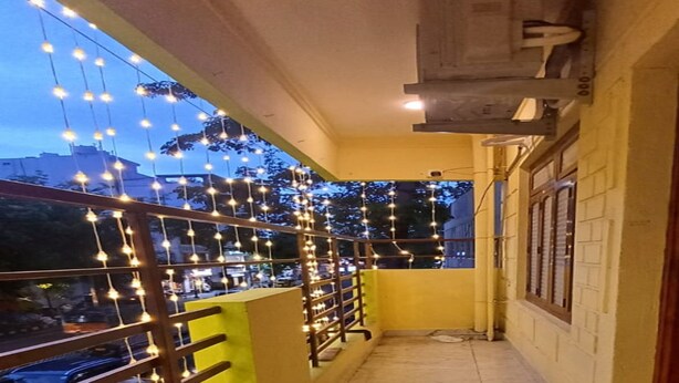 A corridor with a tiled floor, a metal railing, and string lights. - Sun Shine Guest House (Puducherry)