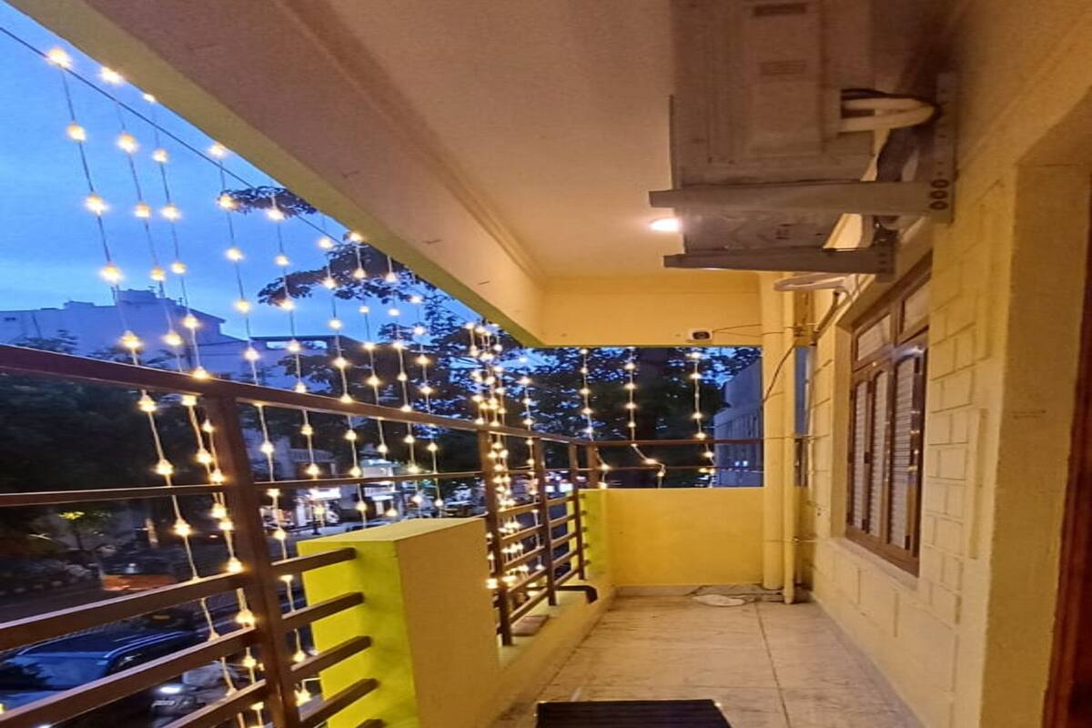A corridor with a tiled floor, a metal railing, and string lights.