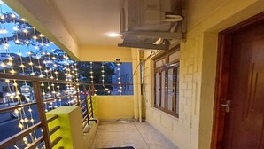 A corridor with a marble floor, a metal railing, and a door on the right. - Sun Shine Guest House (Puducherry)