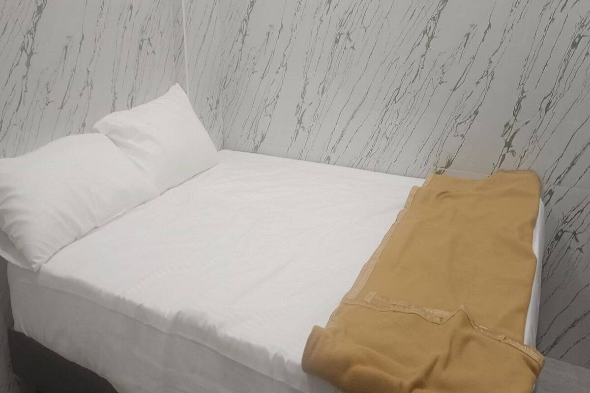 A bed with white bedding and a mustard-colored blanket.