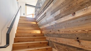 A wooden staircase with a metal handrail and a wooden wall with visible knots and grain patterns.