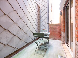 Un petit espace extérieur aménagé avec une table et des chaises, un sol carrelé et un mur en briques.