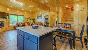 Ein Holzblockhaus-Interieur mit Küchenbereich, Esstisch und Sitzgelegenheiten.